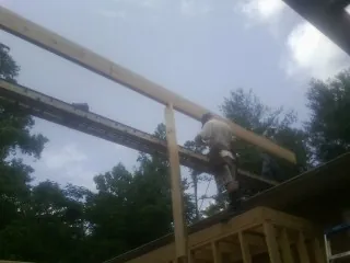 Carpenter setting a ridge beam over a new addition frame — Ice Dam Removal by Roofing Brothers in Iron City