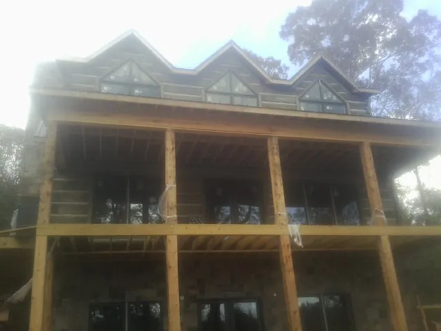 Dormers and porch framing on a large log home under construction — Roof Coating work by our crew in Iron City